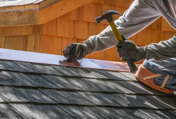 A man is using a hammer to work on a roof, demonstrating construction skills and focus on his task for roofing services in Marietta, Georgia.