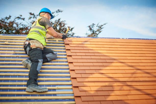 A man carefully works on a roof, using a ladder for support and safety during his task for roofing services in Marietta, Georgia.