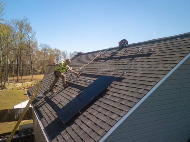 A man is diligently working on the roof of a house, focused on his task amidst a clear blue sky, showcasing roofing trends in Atlanta, GA.