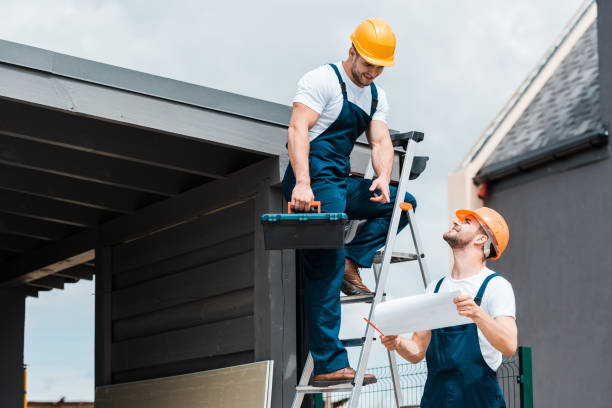 Two men in hard hats and overalls are positioned on a ladder, engaged in a work-related task, showcasing roofing trends in Atlanta, GA.