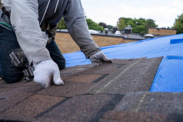 A man installing an asphalt roof on a house, using tools and materials for the roofing process.