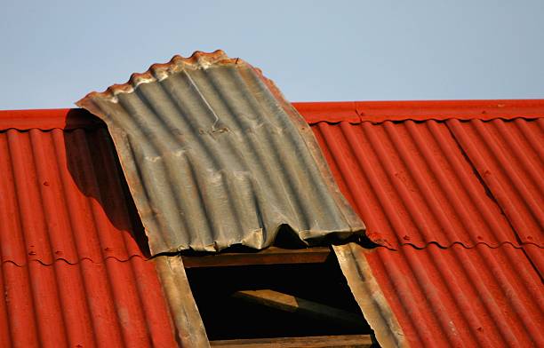 A red building with a metal roof and a window, highlighting issues related to metal roofs.