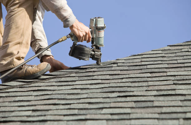 A man uses a nail gun to install shingles on a roof for an affordable roofing company.