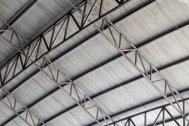  Two men repairing a metal roof under a bright sun, representing a metal roof repair company at work.

